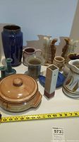Overview of pottery items including vases, jugs, casserole dish, candlesticks, and onyx bookends.