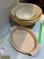 Overview of oval Le Creuset casserole dish with handles and three nested mixing bowls on tabletop