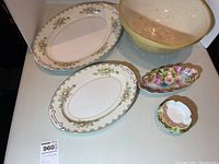 Photo showing all five items: two oval platters with floral and gold details, one yellow mixing bowl with floral interior, two small candy dishes with floral and gold accents.
