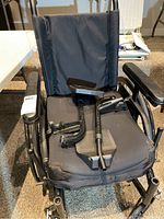 Front view of the wheelchair showing black fabric seat and backrest, footrest placed on seat.