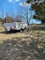 Exterior side view of folded camper showing body, wheels, hitch and spare tire