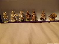 Photo showing 7 Wade Red Rose Tea ceramic figurines, various animal and human characters lined up on a flat surface.