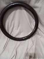 Full view of the circular dark brown faux snakeskin steering wheel cover placed on a light fabric surface.