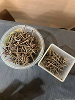 Two plastic containers filled with assorted metal screws of varying lengths and types, showing signs of usage and some rust.