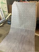 Photo showing the entire backdrop held up in a storage or warehouse setting, highlighting the tile and floor pattern and approximate size.