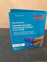 Box front showing product name Rapid Relief and description of reusable hot and cold gel slippers in French.