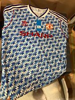 Front view of blue and white lightning pattern Manchester United soccer jersey with Adidas and Sharp logos and embroidered club crest.