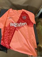 Front view of pink Nike FC Barcelona soccer jersey with red graphic pattern, Nike swoosh logo, FC Barcelona crest, and Rakuten sponsor logo.