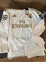 Front side of the white Adidas Real Madrid soccer jersey with Fly Emirates logo and UEFA Champions League patches on sleeves.