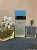 Photo showing three perfume bottles from left to right: Marc Jacobs Daisy, Dolce & Gabbana Light Blue, and Miracle bottles.