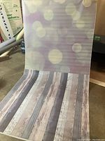 Photo of purple bokeh patterned seamless vinyl backdrop rolled out, showing soft circular light patterns and wood plank pattern at bottom.