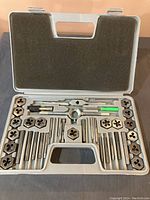 Open tap and die set displaying all taps, dies, wrenches and accessories inside a foam-lined grey plastic case.