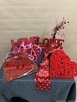 Valentines decor props arranged on table with various heart and LOVE motif decorations.