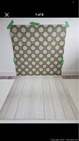 Full view of green backdrop taped to wall with white large polka dots and light wood patterned floor extension below.