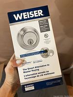 Photo of closed box for Weiser deadbolt lock showing brand and marketing information about SmartKey features and rental property suitability.