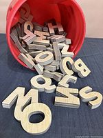 Wooden letters spilling from red container showing the layered plywood construction and block style letters.