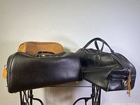Photo showing three vintage leather gym/carrying bags from a side angle on a white background.