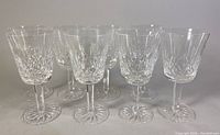 Front view of all eight crystal goblets arranged side-by-side showcasing the cut pattern and clarity.