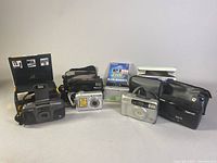 Overview photo of all five cameras in the lot, showing various digital and 35mm film models including Nikon, Samsung, Sony, FujiFilm.