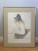 Full view of the framed watercolour artwork showing the nude woman in a blue hat sitting on a chair.
