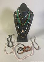 Full lot of multiple vintage semi-precious stone bead necklaces and bracelets displayed on mannequin and laid flat, showing variety in colors and styles.