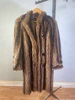 Front view of a vintage ladies long raccoon fur coat with three buttons.