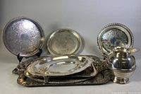Overview of all silver plated servingware items including trays and pitcher in various shapes and sizes