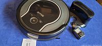 Top view of Shark robot vacuum with included battery and charging dock on a blue surface.