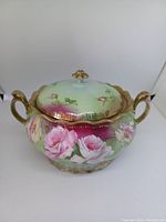 Front view of the covered dish showing floral hand-painted decoration, gold accents, and overall design.