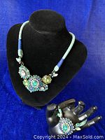 Full view of necklace on display bust and bracelet on hand display showing set appearance and style.