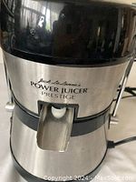 Front view of the stainless steel and black plastic electric juicer with logo visible