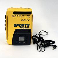 Front view of the yellow Sony Sports Walkman with FM/AM frequency labels, solar alarm clock display, and attached earphones.