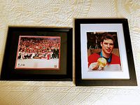 Two framed items displayed side by side on a white wall. Left is the group photo of Team Canada, right is the signed photo of Sidney Crosby.
