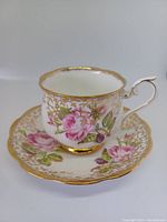 Teacup and saucer set showing pink rose floral pattern and gold accents on white bone china