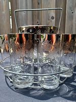 7 highball glasses with silver ombre and floral etching arranged in a circular metal caddy.