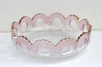 Side view of the antique American pressed glass bowl showing scalloped rim with gold trim and circular pink accents.