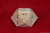 Front view of carved stone cube incense holder showing floral carved designs and incense holes on top.