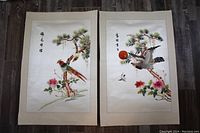 Pair of embroidered silk panels laid flat, showing birds on pine trees with flowers and calligraphy, approx 14.5 x 22 inches each