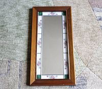 Image of the full rectangular framed wall mirror featuring a solid wood outer frame and inner decorative floral tiles with green corner tiles.