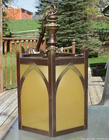 Side view of the pendant lamp showing gothic arch yellow glass panels and bronze metal frame with hanging chain and ceiling mount