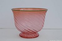 Photo of pink art glass bowl showing clear pink swirl pattern and green rim on bowl's mouth with textured base.
