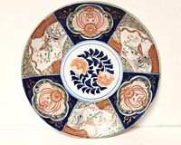 Full view of the round Japanese Imari charger showing the painted floral decoration and blue and gold ornamental panels.