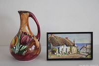 Photo showing both the pottery jug with tulip design and the framed cottage painting together