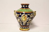 Front view of Italian faience pottery jar showing ornate painted medallion and decorative motifs in vibrant colors.