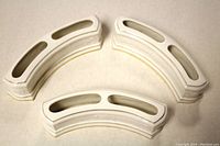 Three small white curved porcelain pansy ring planters arranged showing the top cut-out openings.