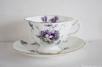 Side view of vintage porcelain teacup with violet floral design and gold trim