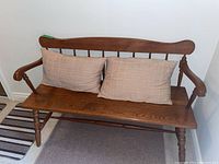 Wooden bench with two beige checkered cushions on seat, showing full front view