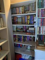 Five shelves of books with a mix of hard and paperback covers, showing diverse titles and authors.