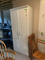 Front view of the white veneer cabinet with two doors closed, showing overall structure and condition.