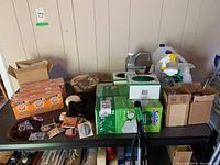 Cleaning supplies on a table including boxes of Swiffer cloths, baking soda boxes, spray bottles, jugs of cleaner, and fridge magnets.